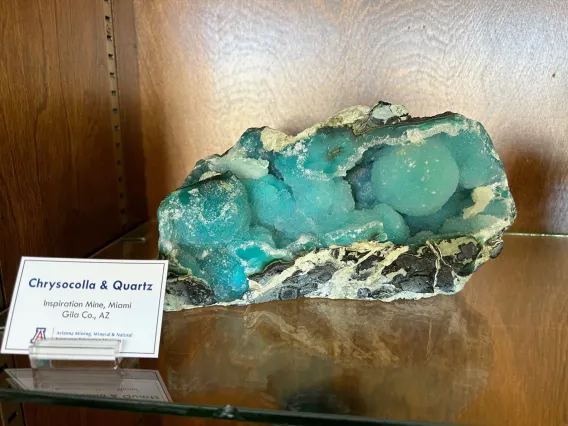 Specimen of chrysocolla and quartz in case.