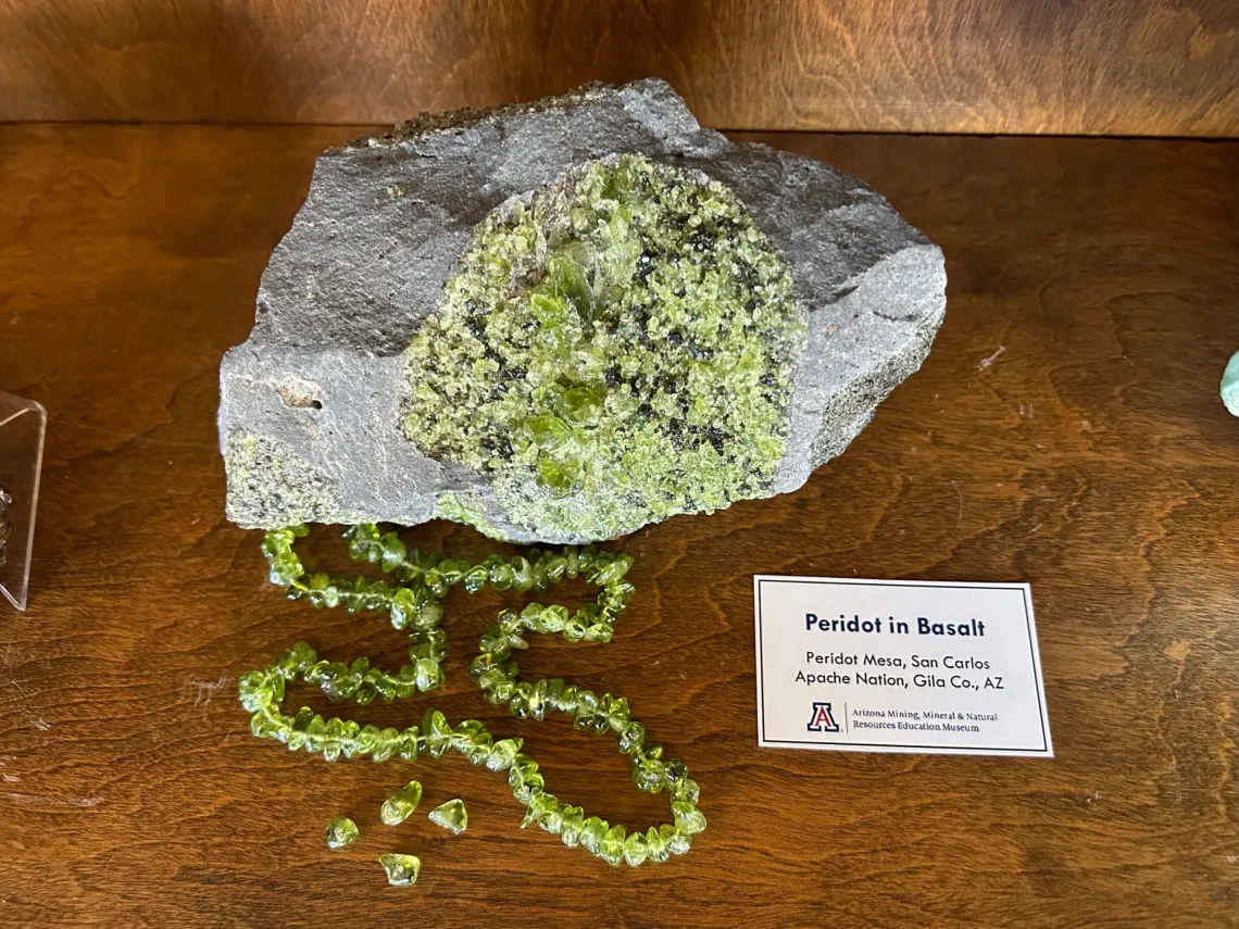 Specimen of peridot in basalt in case.